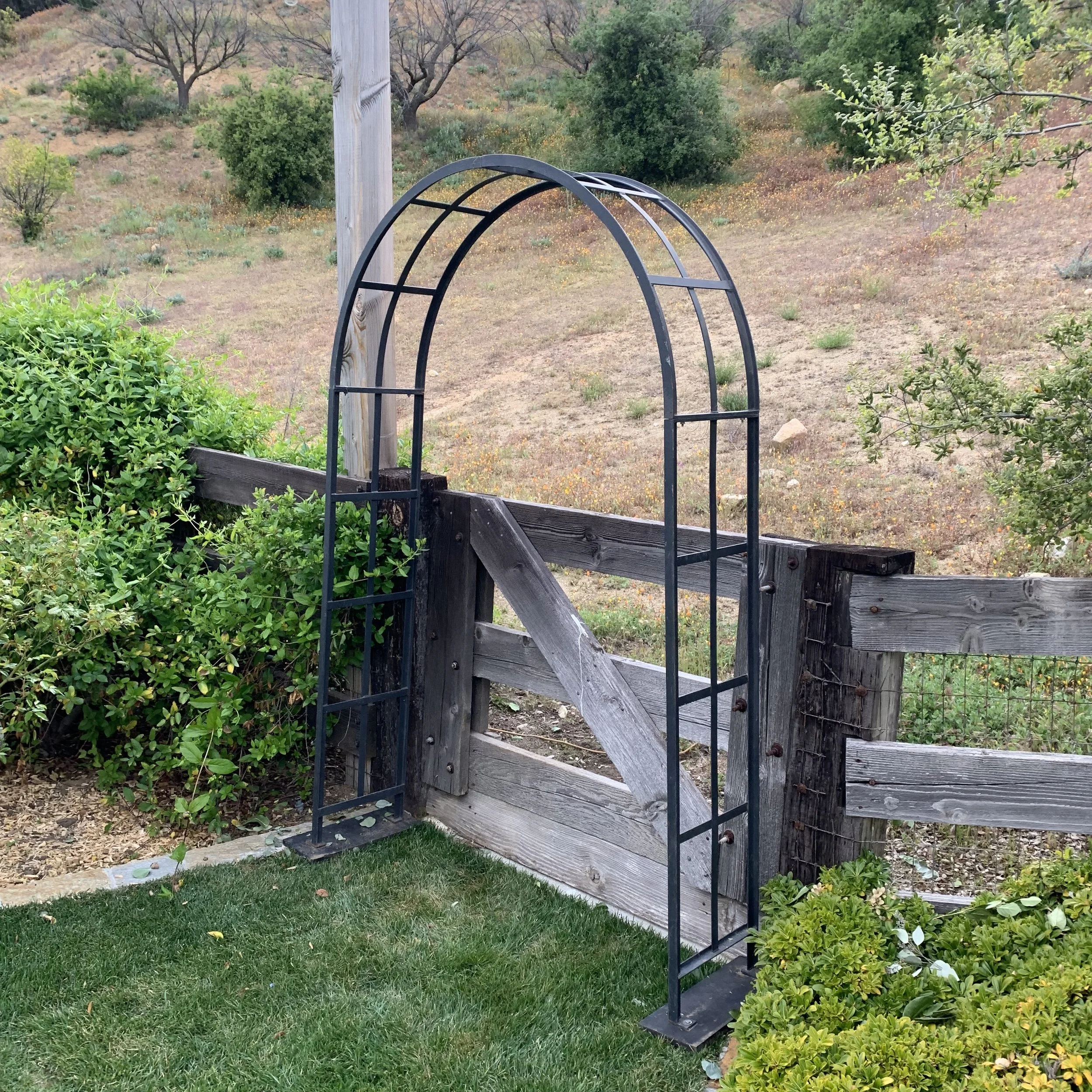 Trevor Perfect backdrop for both ceremony and reception. Free standing black iron arch. Looks great with added floral, fabric, or ribbons. Sides: 14" wide x 84" tall.
