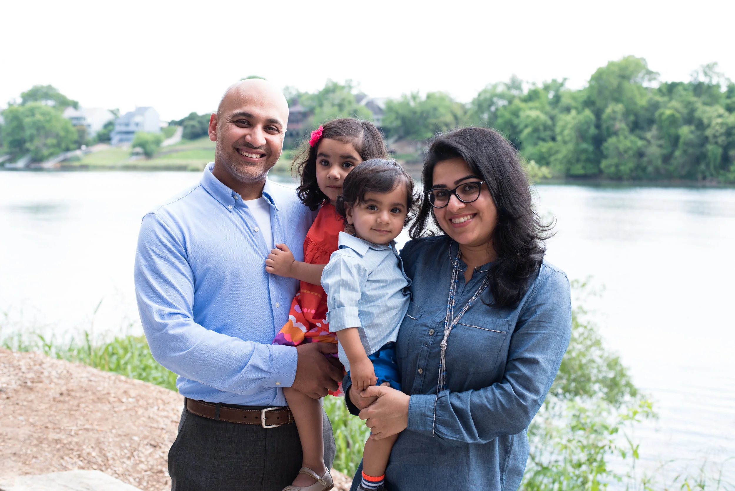 Mom and dad holding children in front of a river.