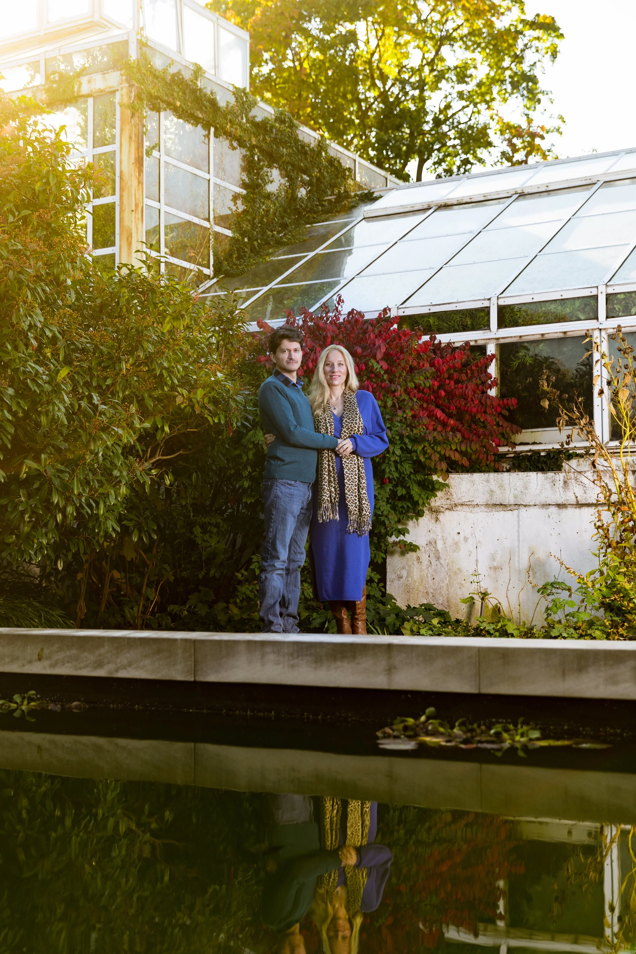Couple standing in front of greenhouse with plants