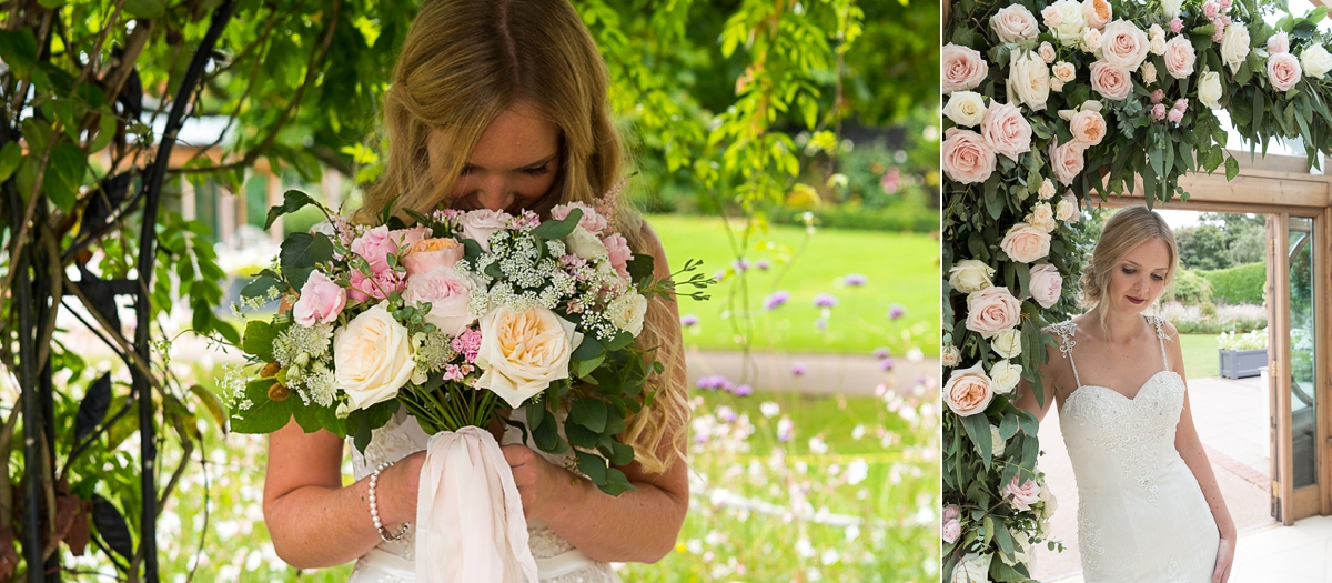 Bride holding bouquet of roses and standing in rose archway at Gaynes Park
