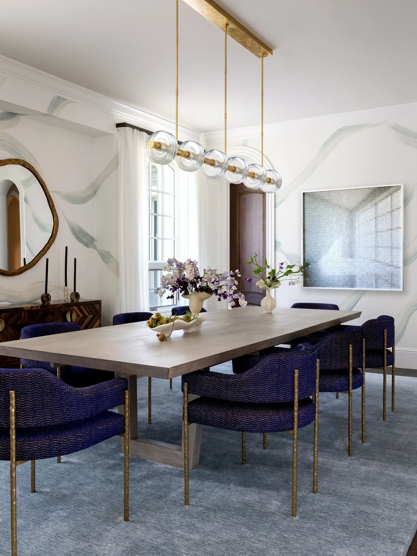 A dining room designed for gathering.
This space blends custom interior design with a balance of modern elegance and timeless detail—from the sculptural brass lighting to the textured blue chairs and soft neutral finishes. Every piece was chos