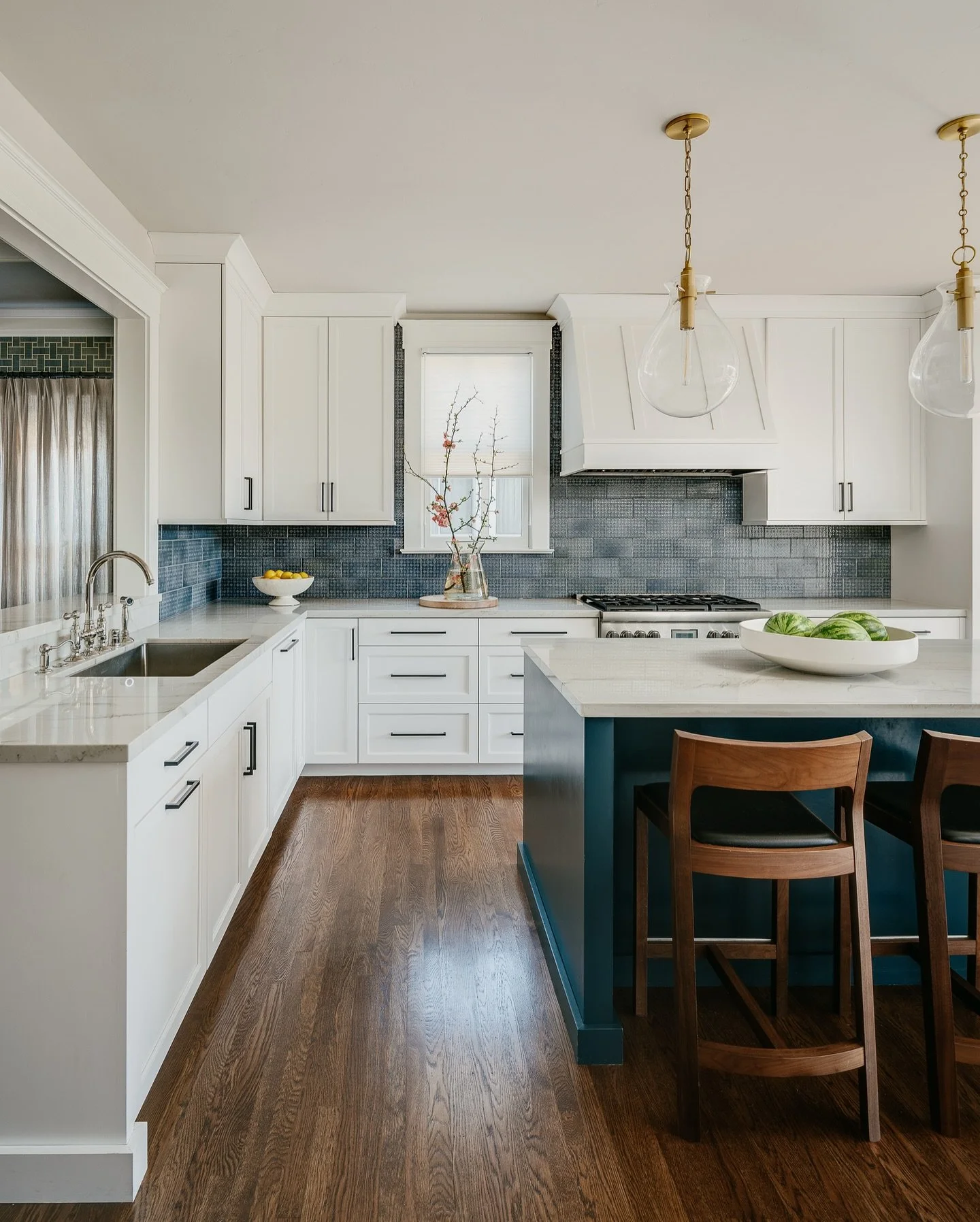 A modern take on a classic craftsman kitchen.

This space balances tradition and warmth with clean lines, white cabinetry, and a deep blue island that anchors the design. Brass accents and natural wood floors bring depth and character, while the subt