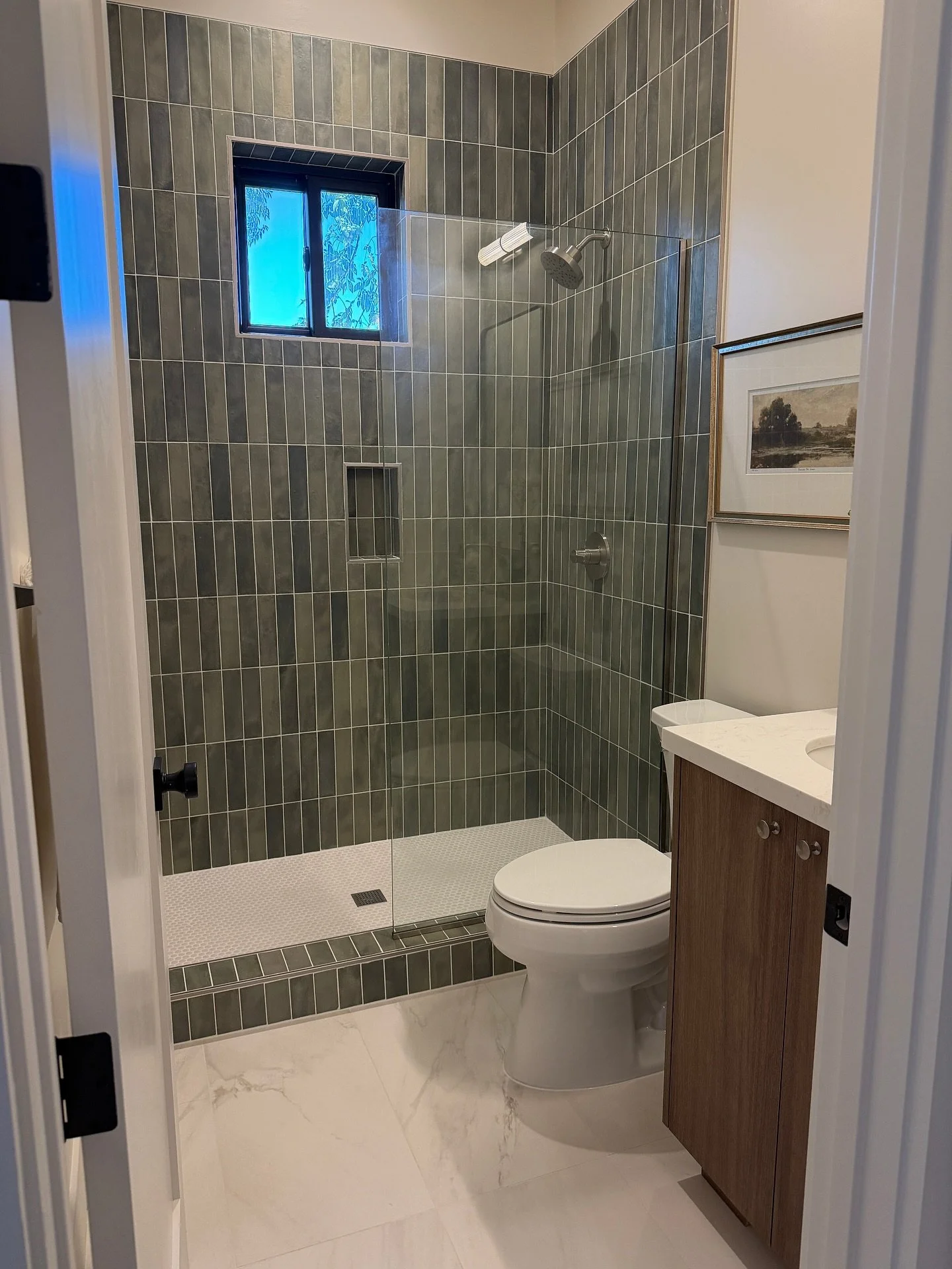 Each bathroom in this home carries the same design DNA &mdash; clean lines, layered materials, and subtle moments of color and pattern.

From natural stone flooring to soft green and blue cabinetry, the finishes flow seamlessly from one space to the 