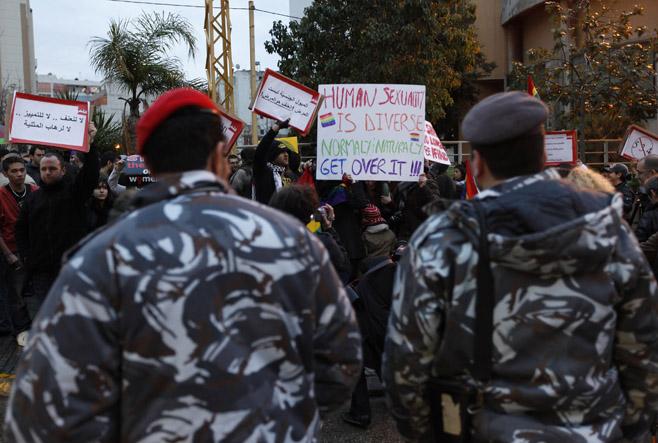 In this Sunday, Feb. 22, 2009 picture, Lebanese police stand guard as protesters carry banners during a sit-in for gays and lesbians in Beirut. In February, about two dozen gays and lesbians held a rare sit-in on Beirut's major intersection of Sodec…