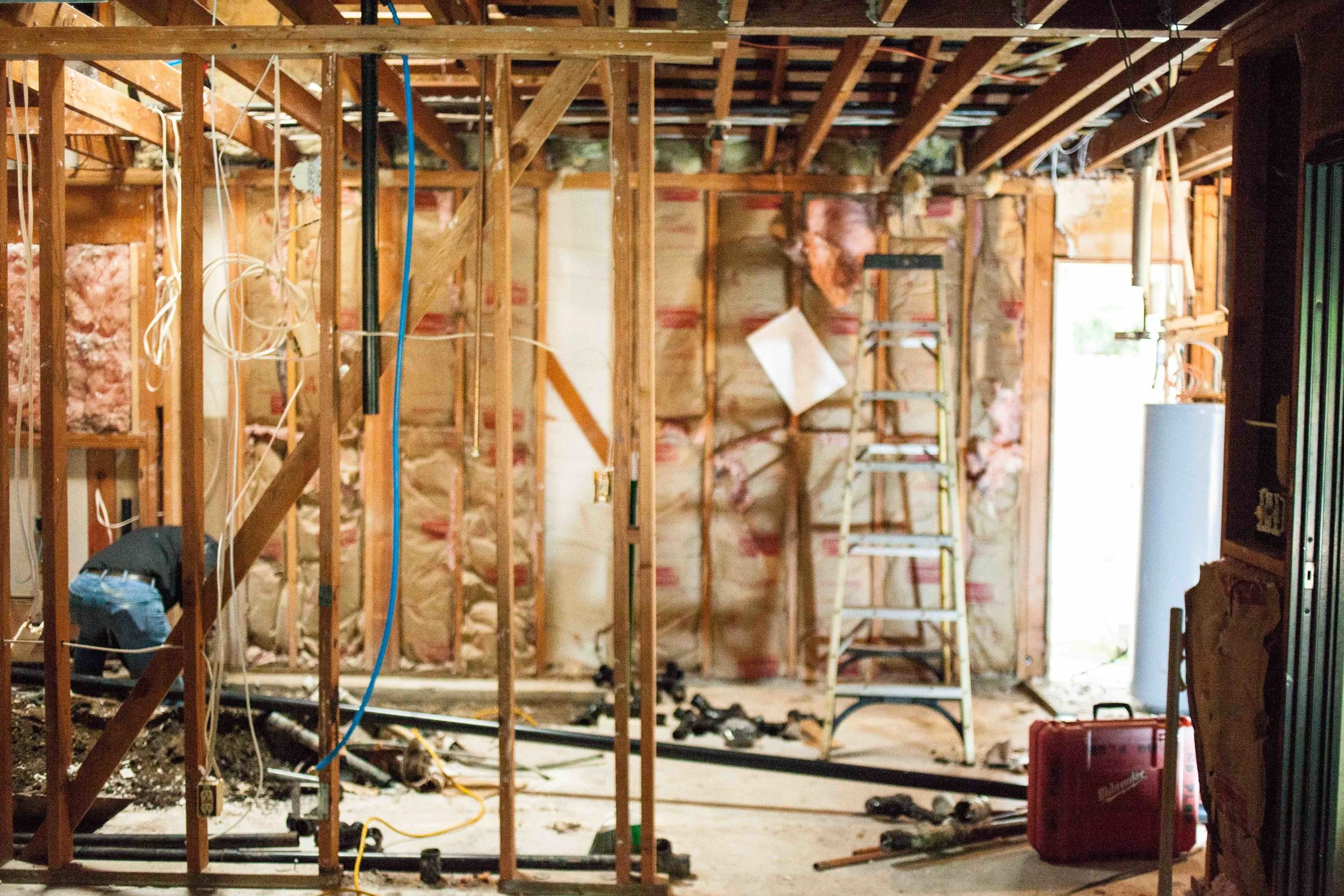 WHAT ARE YOU LOOKING AT? 1. FOREGROUND : EXISTING MASTER BEDROOM 2. STRAIGHT AHEAD & TO THE LEFT: CONCRETE TRENCHING TO PREPARE FOR PLUMBING CHANGES 3. CENTER : PLANS ATTACHED TO THE STUDS...SEEING THIS ALWAYS MAKES ME HAPPY! 4. FAR LEFT: WATER HEATER AND OLD CLOSET STORAGE