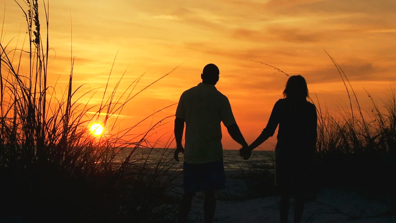 stock-footage-young-ethnic-couple-silhouette-holding-hands-watching-sunset-on-beach-vacation-loving-couple.jpg