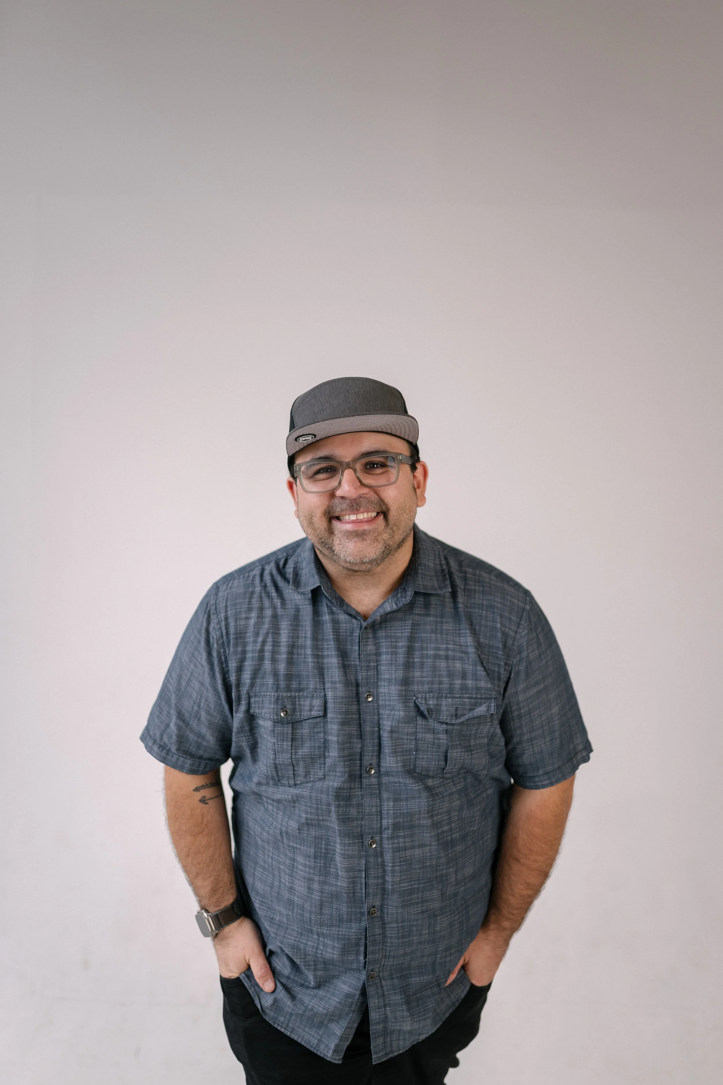 Jason Morales, founder and video producer Bright & Gray Creative, smiling in a studio portrait wearing a gray plaid button-down and baseball cap, representing Birmingham Alabama video production and brand storytelling for businesses across the south