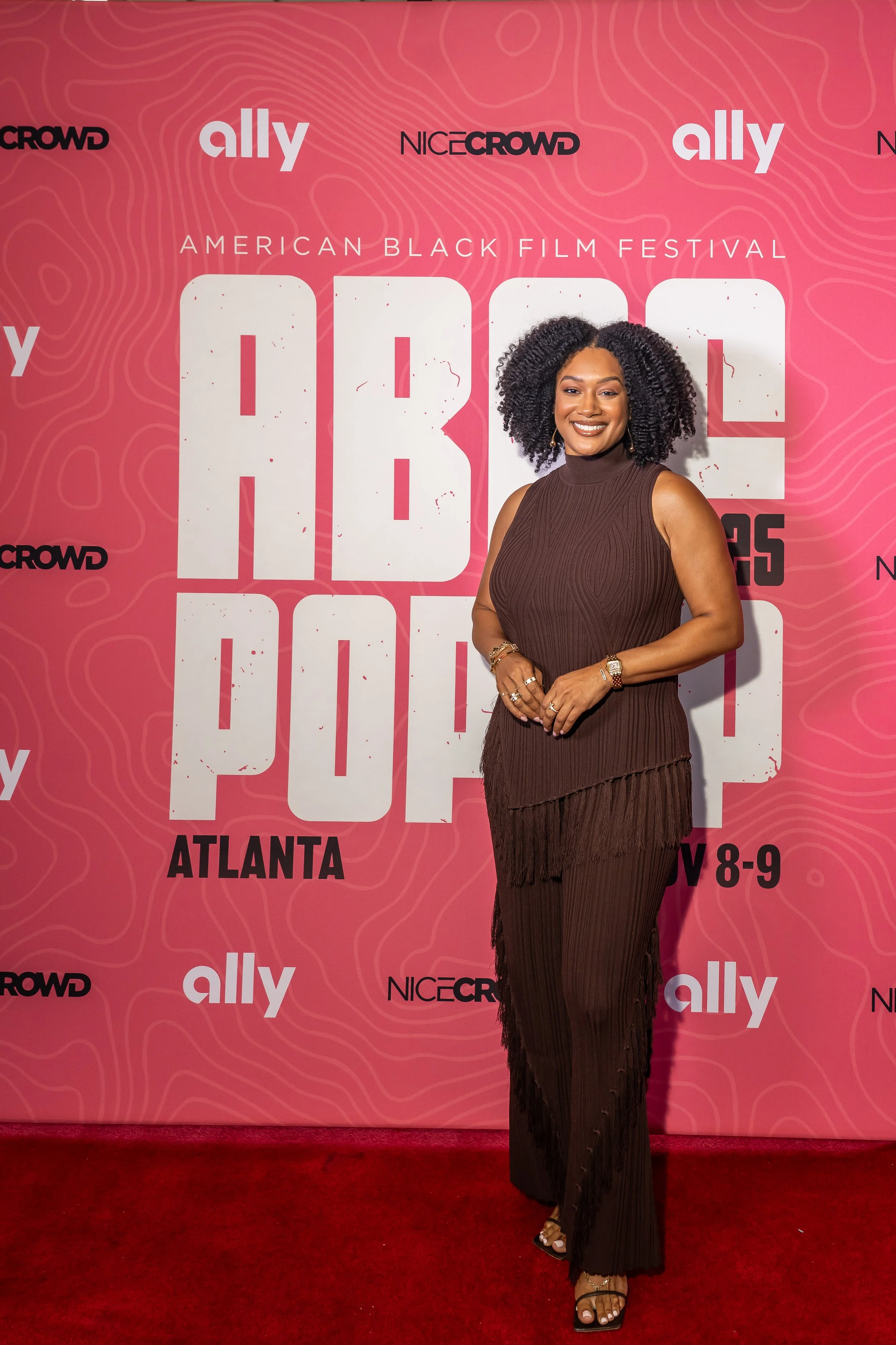 Crystal Renee at the American Black Film Festival in Atlanta, posing in front of a pink backdrop with festival logos and event details.