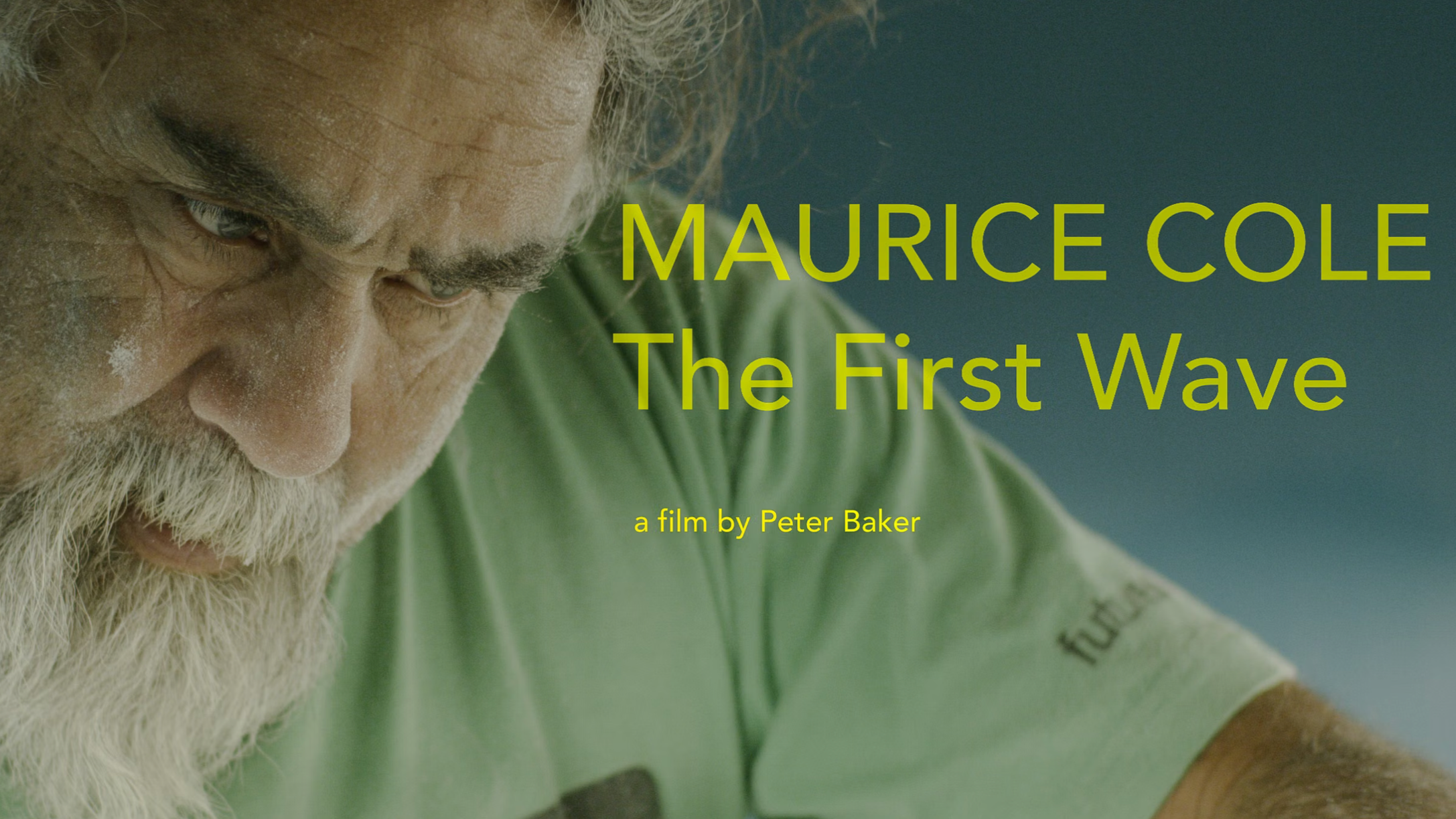 Close-up of an elderly man with a white beard and blonde hair, focused on an activity, with text overlay reading "Maurice Cole The First Wave, a film by Peter Baker."