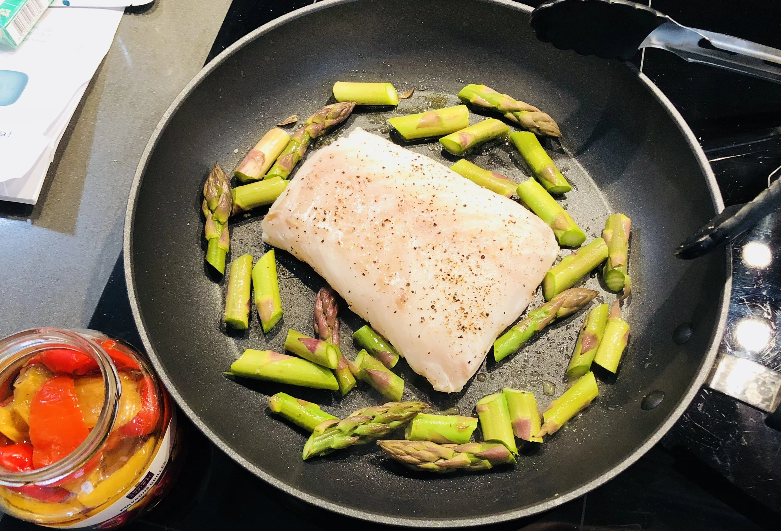Fish frying surrounded by Asparagus (fish seasoned on second side while cooking)