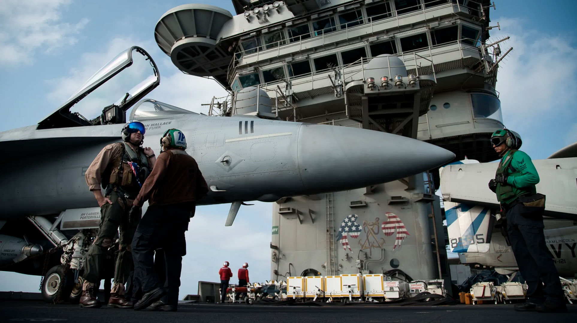 A pilot speaks to a crew member by an F/A-18 fighter jet on the deck of the USS Abraham Lincoln aircraft carrier in the Arabian Sea. Donald Trump has threatened Iran with 'obliteration'. Credit:AP