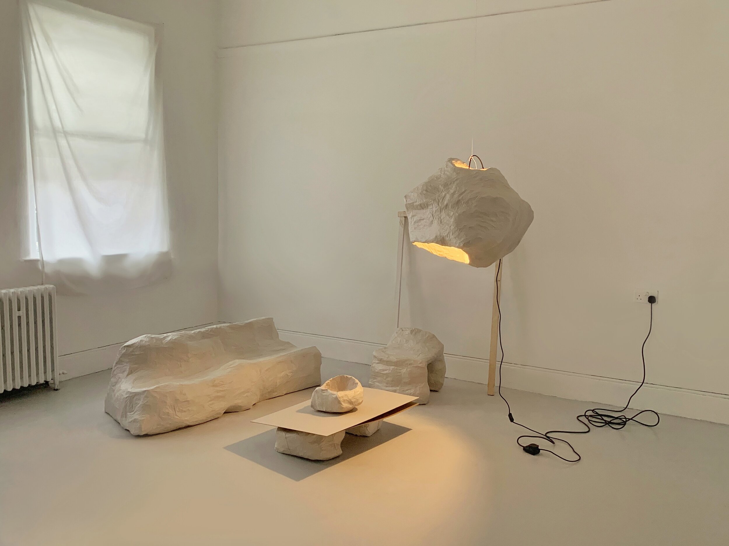   Untitled  (2019)                                                                            newsprint, flour, tape, string, wire, cardboard, wood, lightbulb 
