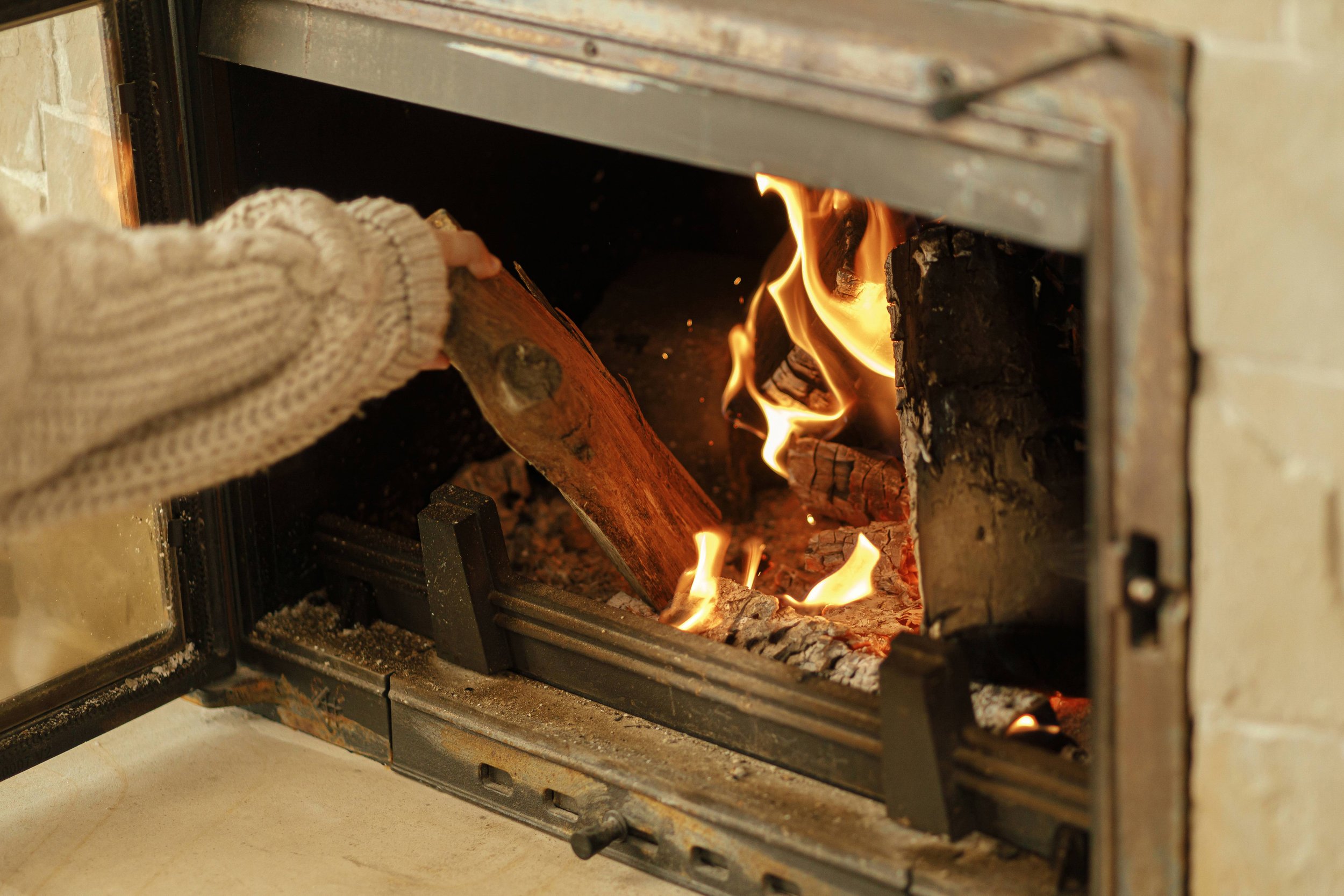 woman-putting-firewoods-into-burning-fireplace-small.jpg