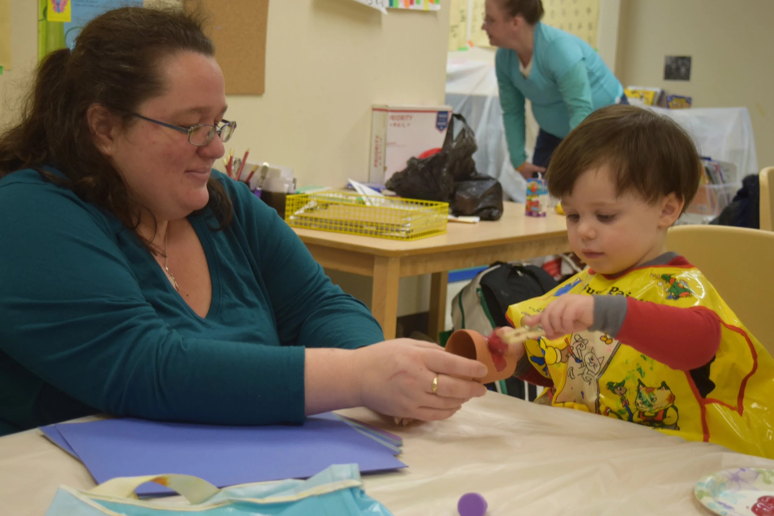 Candice Riggs holds a flower pot as her son, Jasper, paints it.