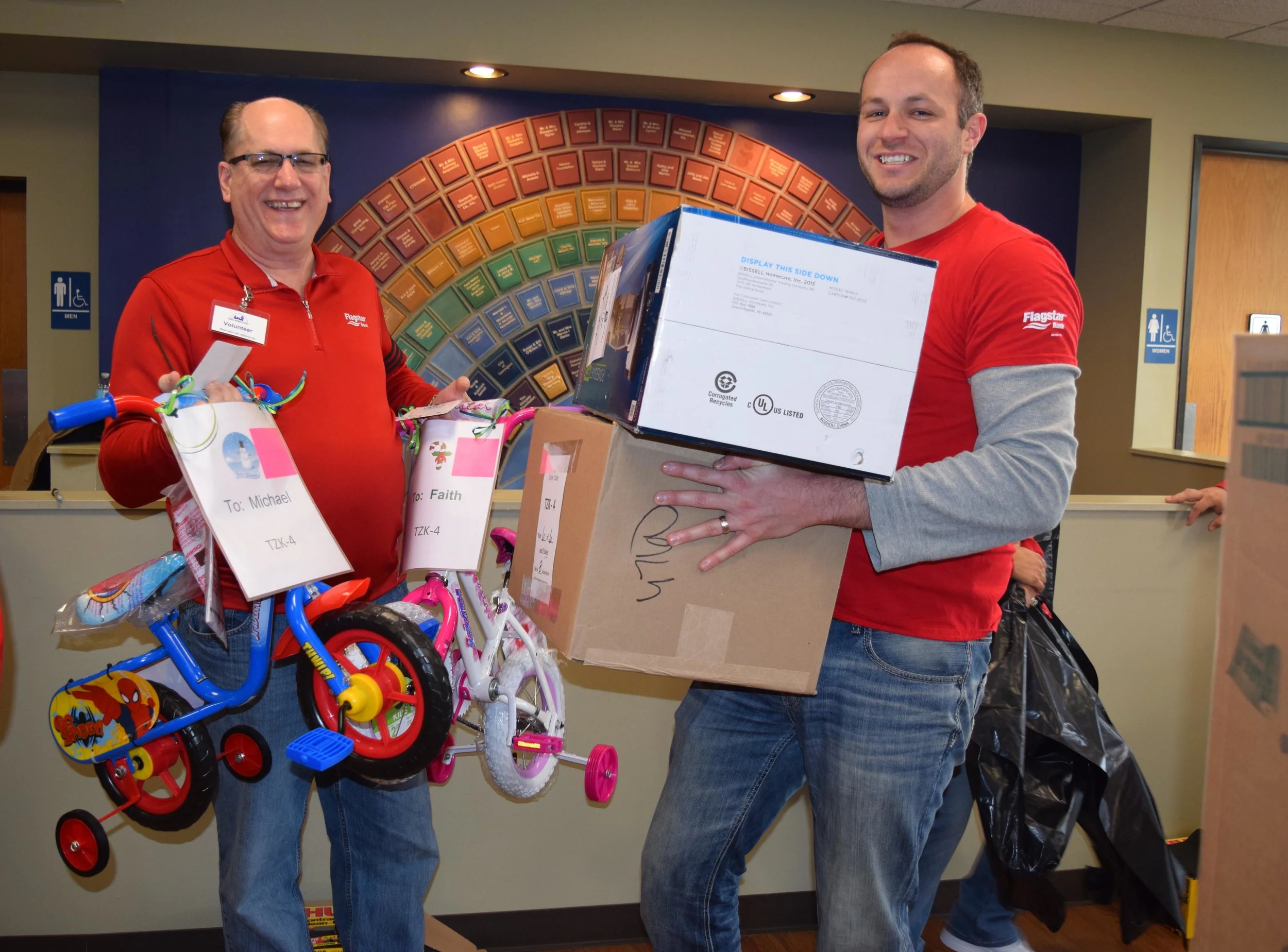 Volunteers carry gifts dropped off for Oakland Family Services’ Adopt a Family program.