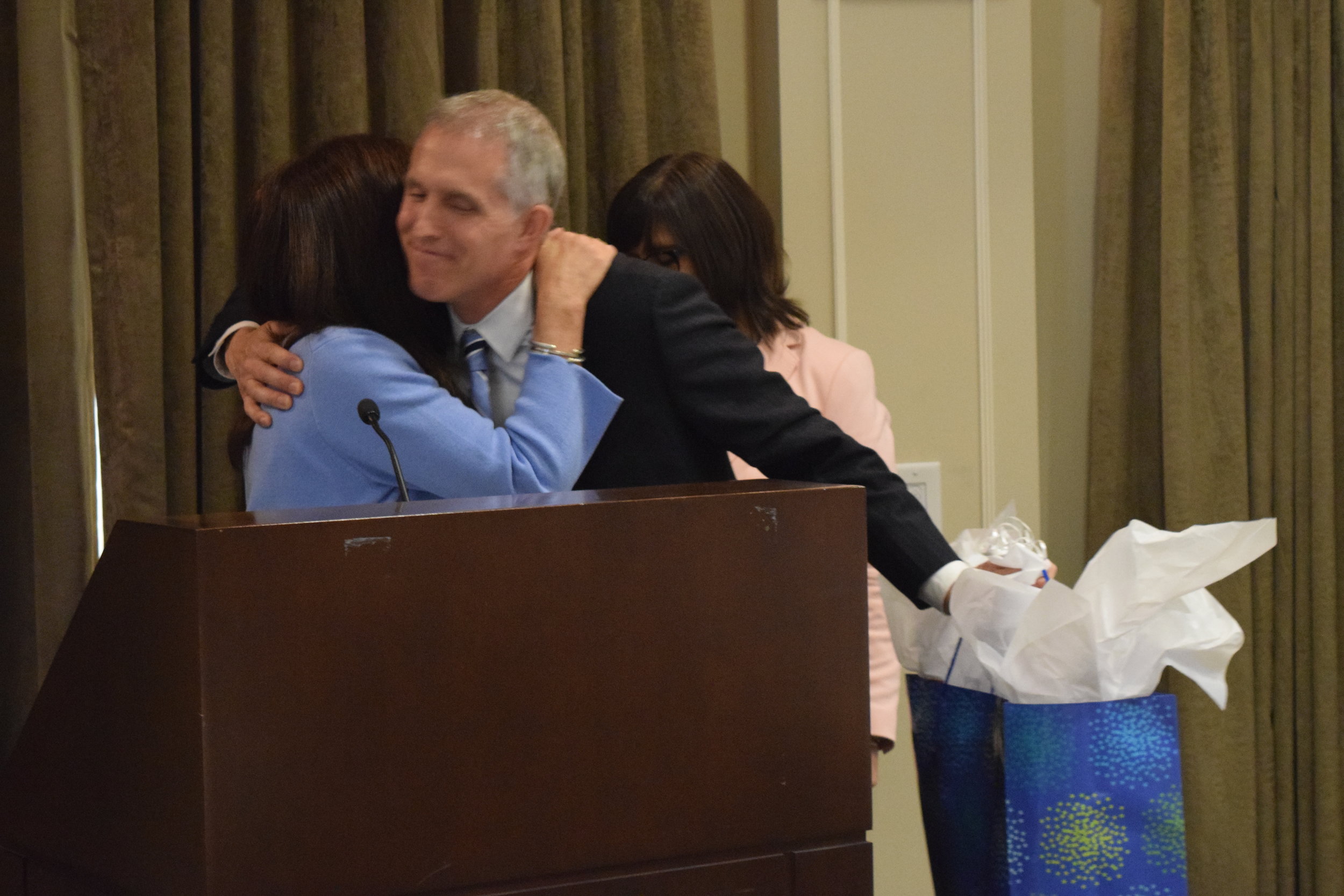 Board Chairman Betsy Meter hugs outgoing Chairman Paul DeRoche.