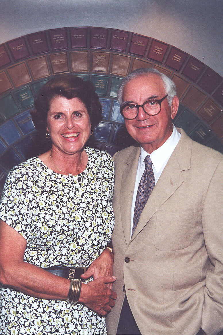  Brigitte and Mort Harris stand in front of the Pewabic tile wall at Oakland Family Services’ building in Pontiac. The wall was installed in 1999 and honors top donors from 1995-2010. 