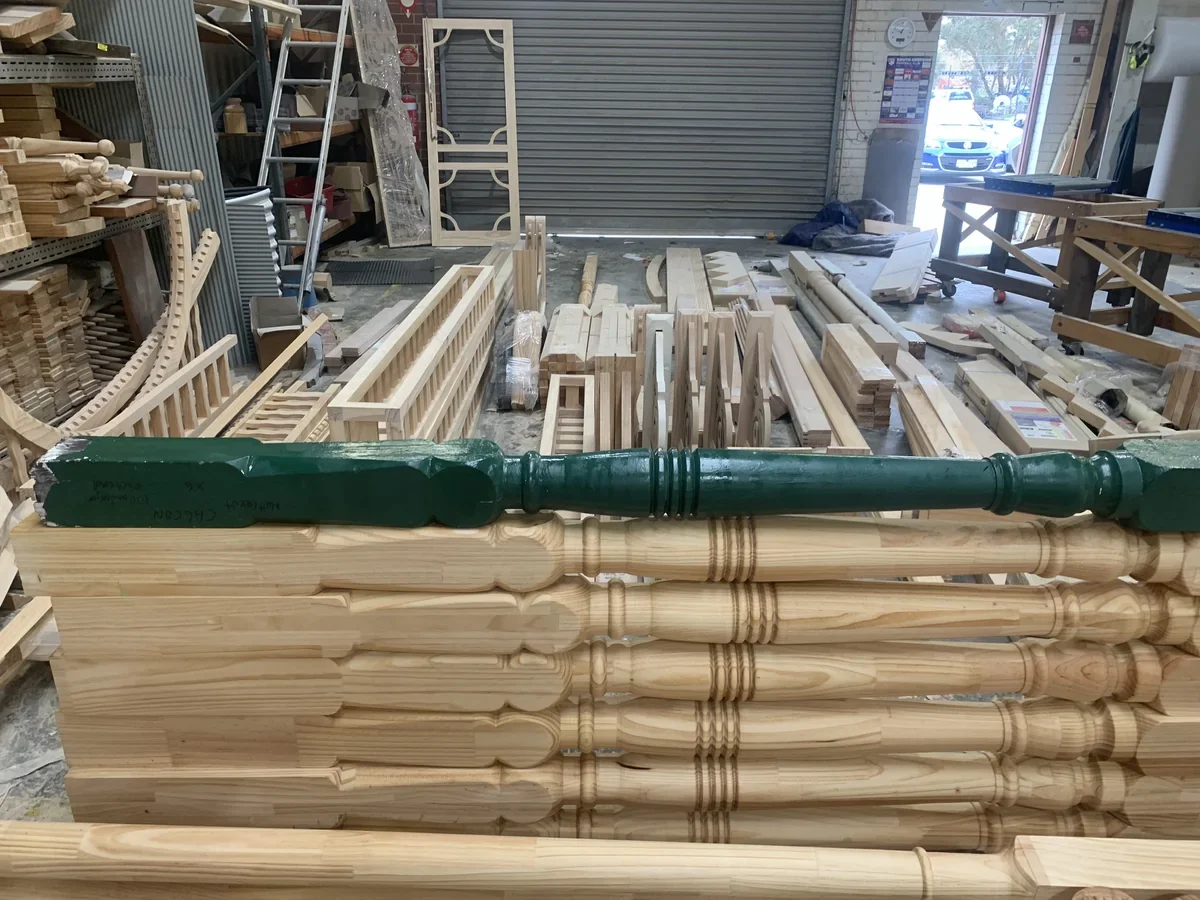 A green painted original laid above newly turned timber posts, showing the corresponding collars and turned sections.