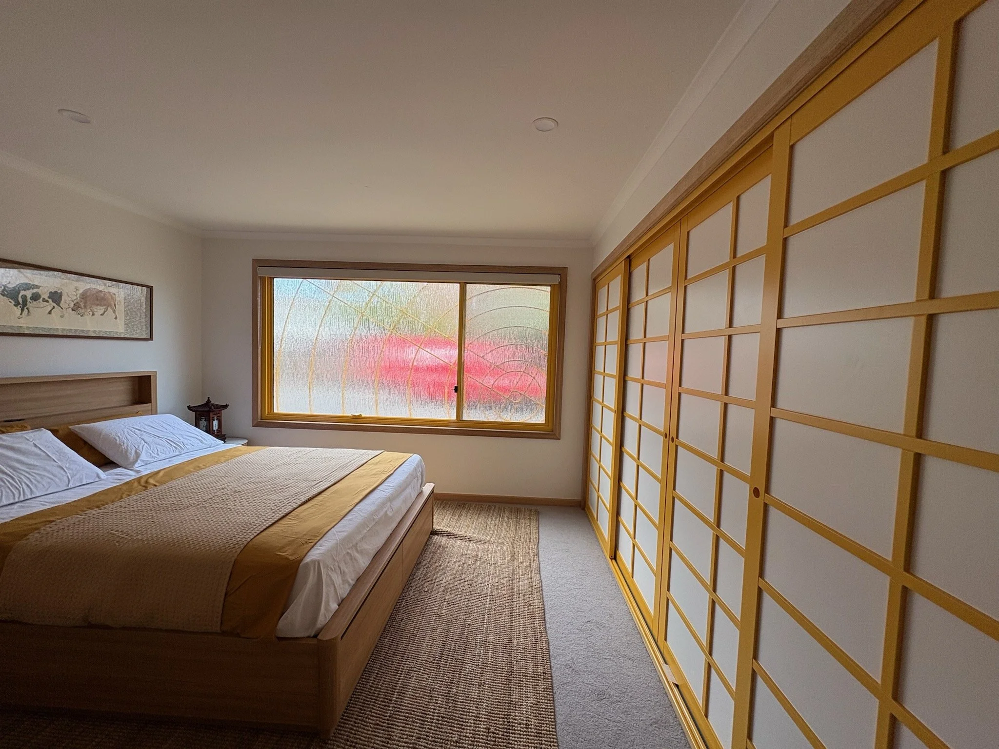 Luxton Architecture — bespoke bedroom interior with Japanese-inspired timber wardrobe, frosted rain glass window and warm accent tones, Melbourne residential design