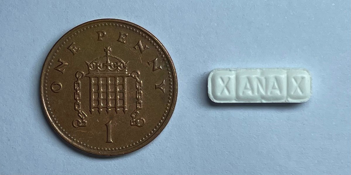 Counterfeit Xanax bar tablet next to a British one-penny coin for scale
