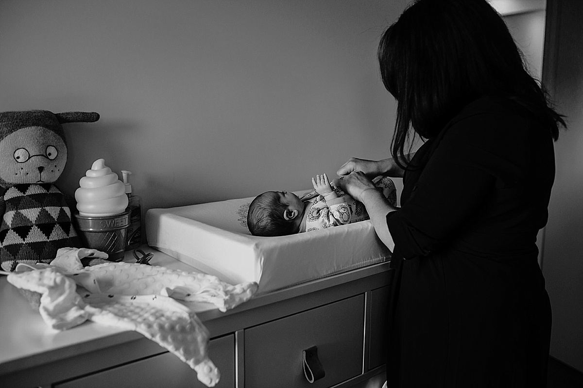 Black and White image of mother undressing newborn on change table