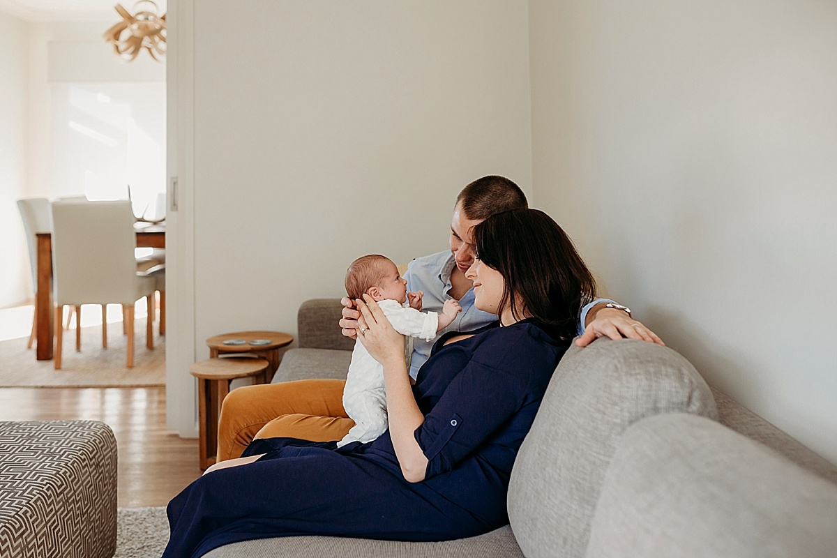 new family sitting on lounge playing with baby