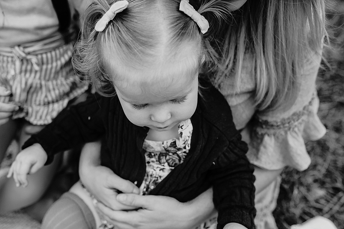 Black and white image of little girl sitting down on mums lap