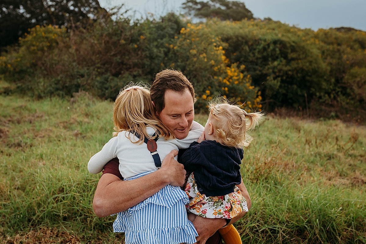 dad and his two daughters hugging him
