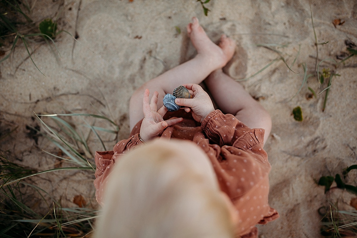 Little girl holding shells on beach