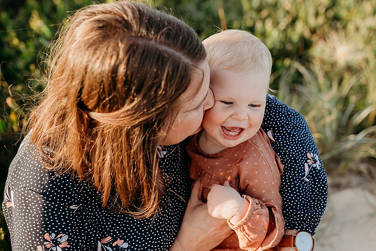 Mother holding daughter and giving her a kiss on the cheek