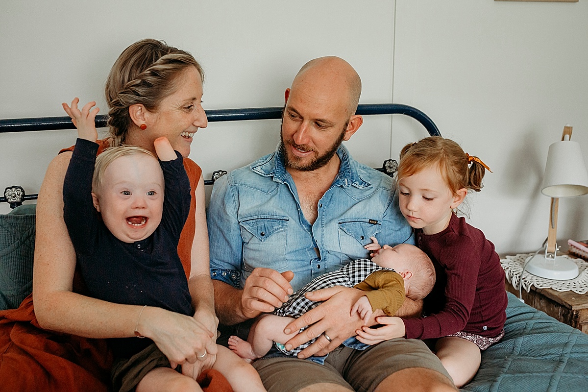Family on bed smiling in newborn session
