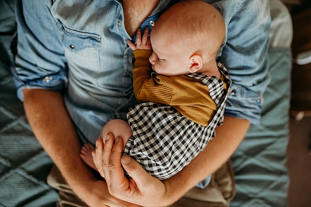 baby curled up on fathers chest sleeping
