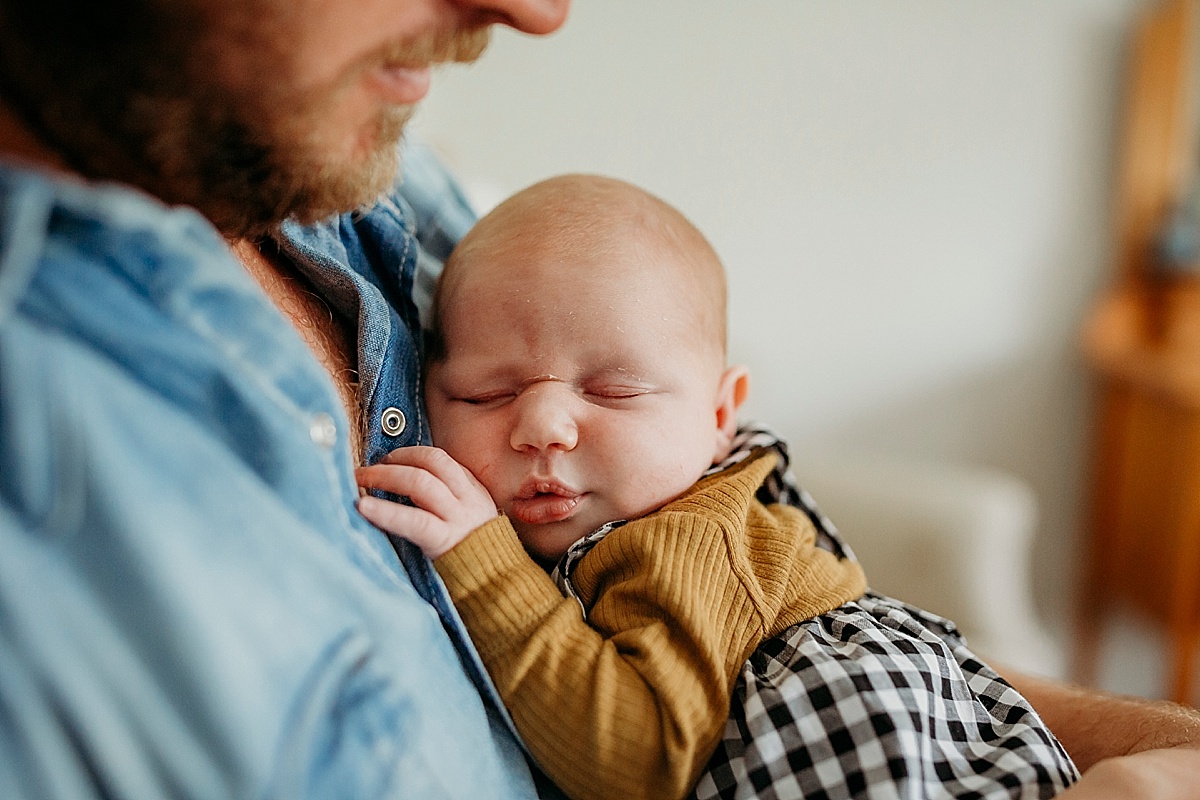 newborn curled up asleep on fathers chest with hand resting near face