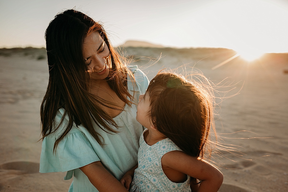 Mother and daughter looking at each other. Daughter sitting on mums lap, sunset, wollongong
