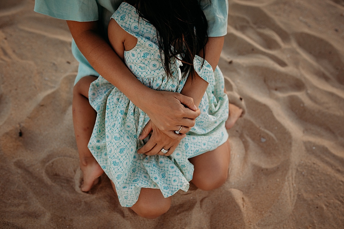 mothers arms wrapped around her little girl sitting on her lap