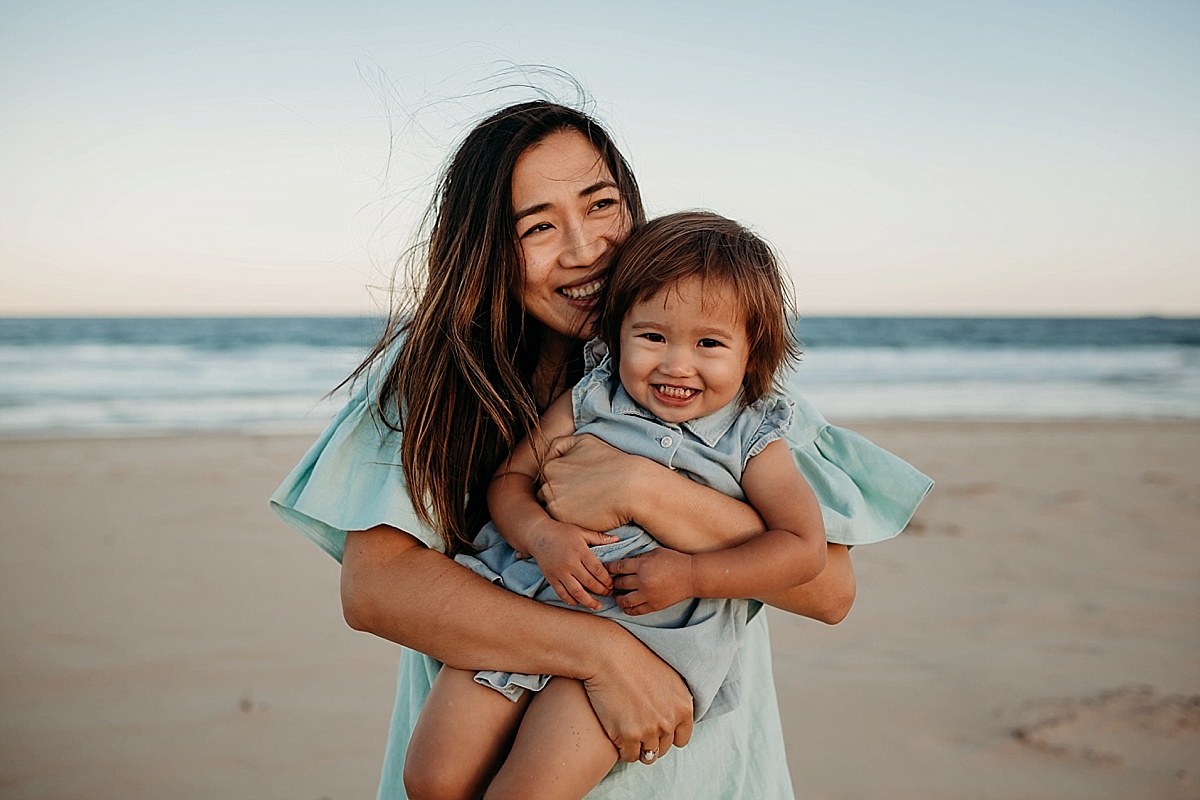mum hugging little girl, picking her up laughing