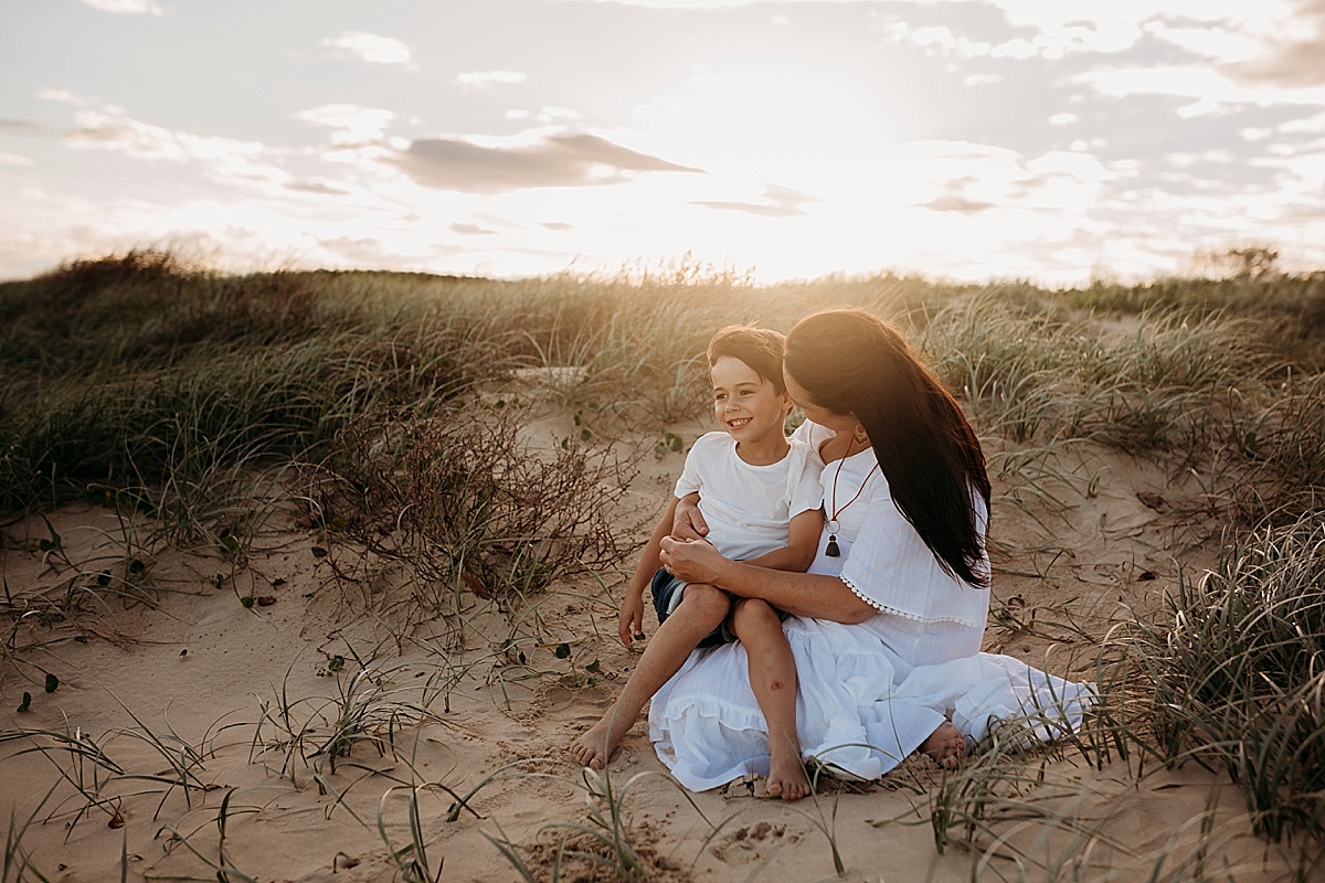 Little boy sitting on pregnant mums lap at port kembla beach