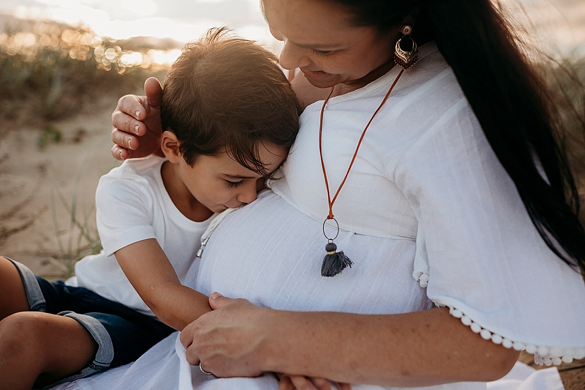 little boy kissing mums pregnant belly