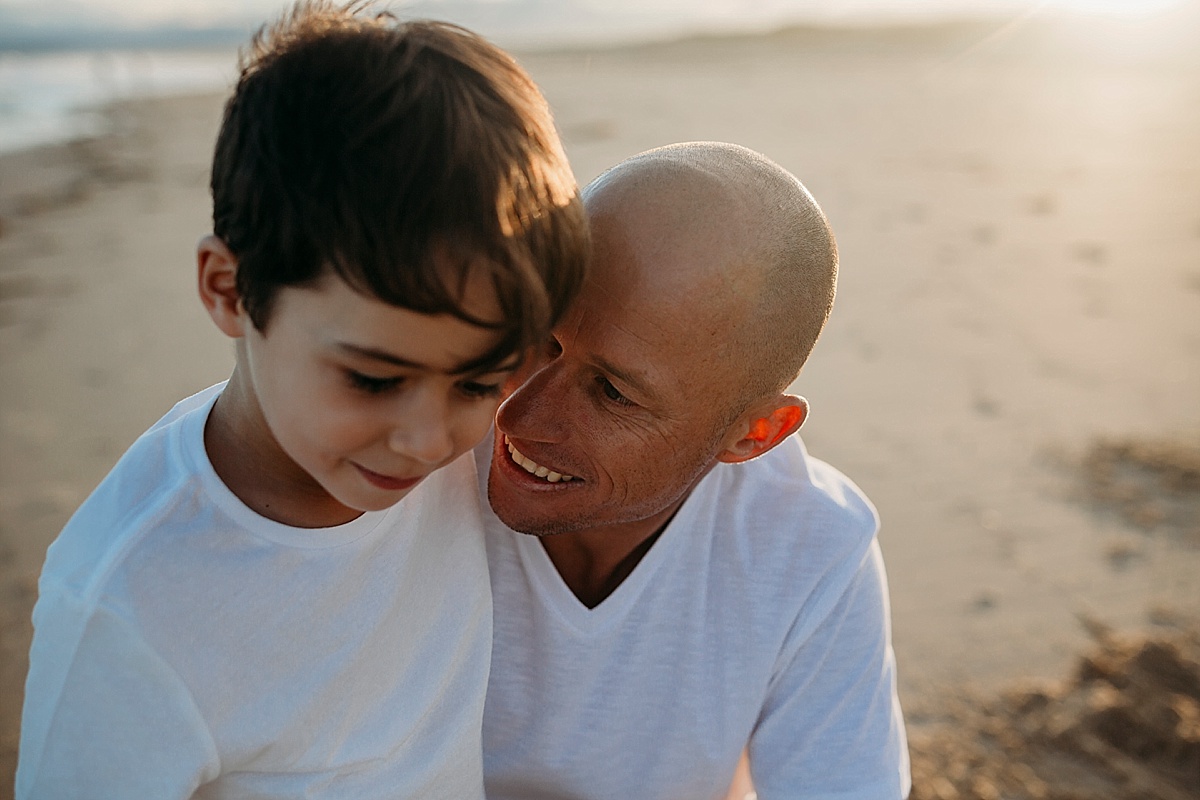 dad holding son in arms at his level, telling him secrets