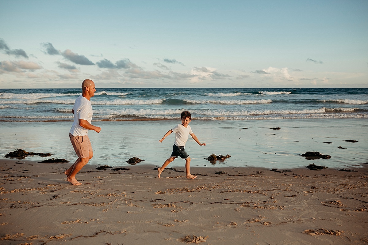 dad and son running along port kembla beach at sunset