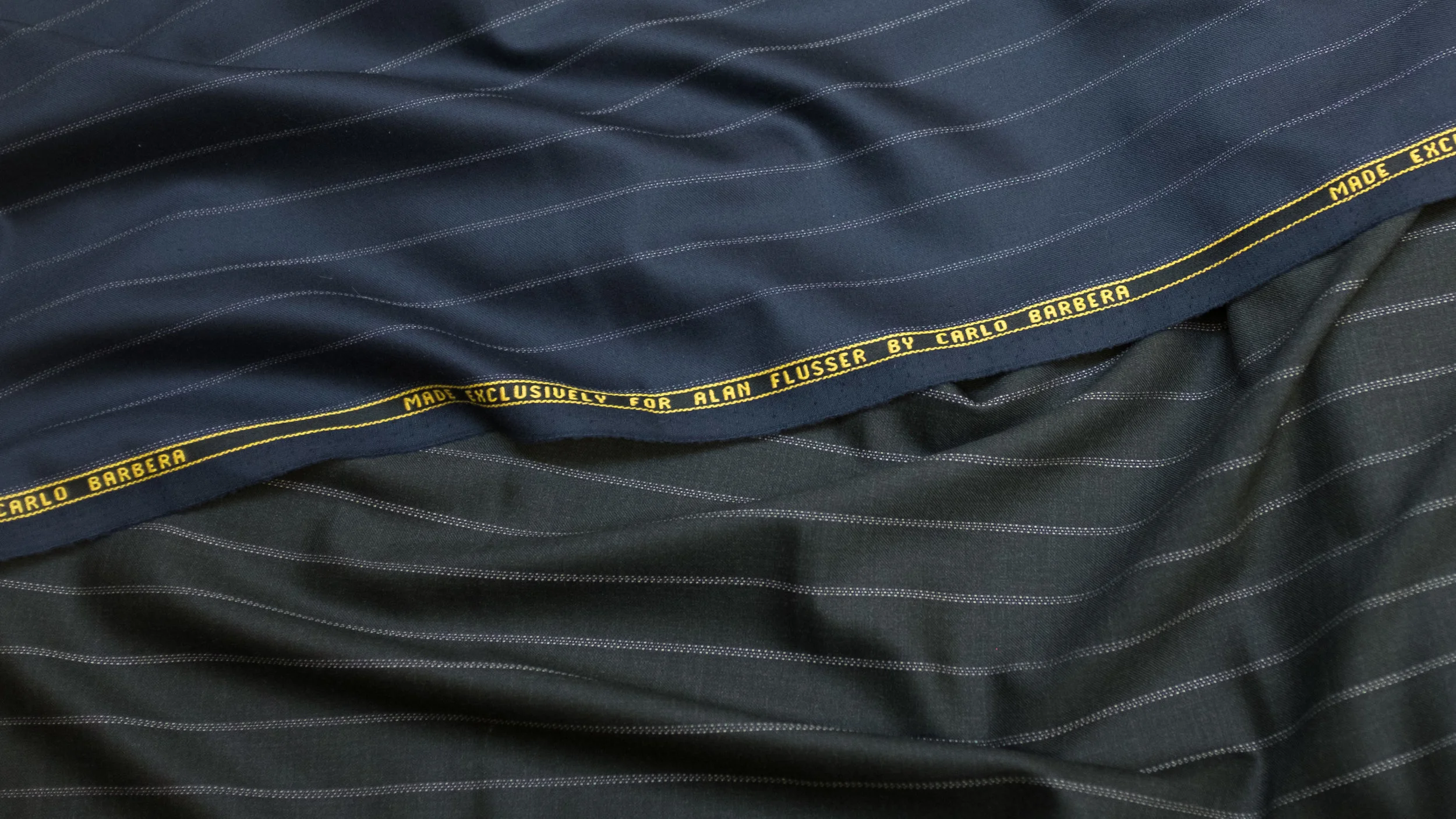 Triple Bead Stripe in Navy or Charcoal - This 9½ oz 120s worsted wool and cashmere is a classic Flusser power suiting, conjuring the elegance of the 1930s with a unique stripe pattern that’s assertive without being aggressive. The softly irregular variations in the stripes give them an unusual hand-woven effect with a subtle sense of movement. Available in classic charcoal with a matte finish, or rich navy blue with a bit of sheen.