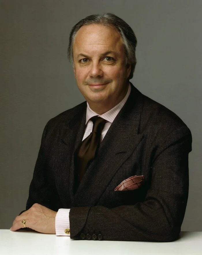 Alan’s pale pink and rich brown ensemble is a model of understated elegance, with subtle details like a horizontally striped shirt and gauntlet suit cuffs marking him as a sartorialist, but not a dandy.