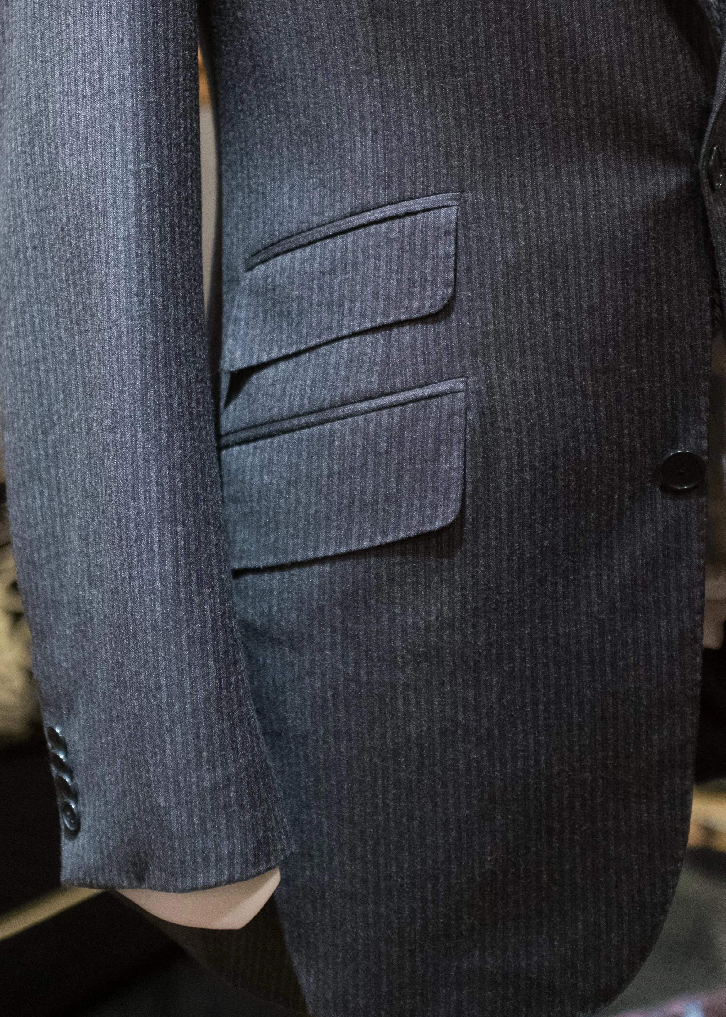 The curved front edge of this single-breasted suit jacket is reflected in the rounded front corner of the pocket flaps.
