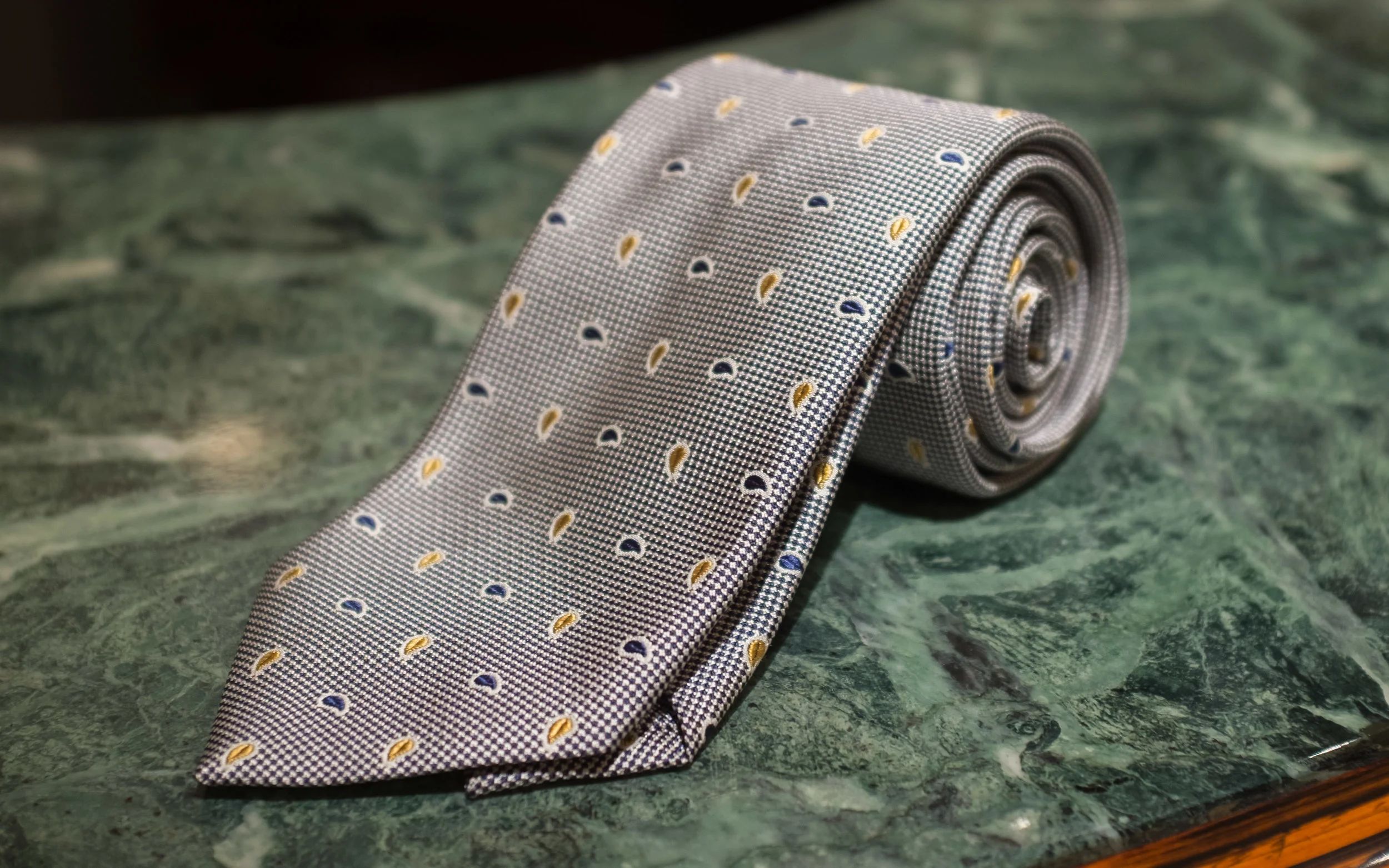 Macclesfield Woven Silk Paisley - The paisley elements here have been abstracted to their geometric essence and reduced in scale to be subtle decorations on a woven black and silver field, making this is a very dressy tie intended to be worn with suits.