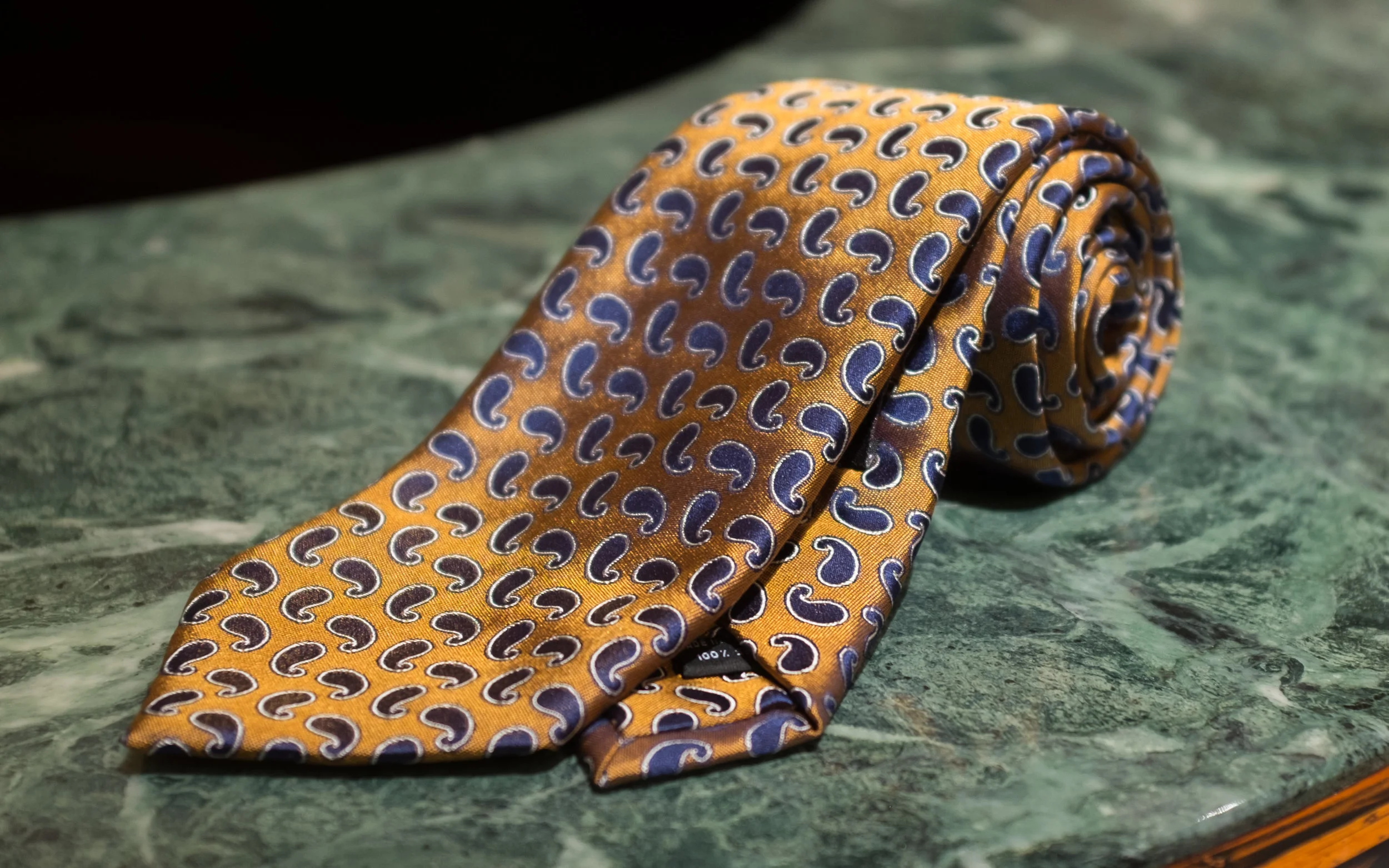Woven Silk All-Over Paisley - A subdued navy paisley motif on a rich gold field makes for a chic tie, dressy but wearable with either a suit or a blazer.