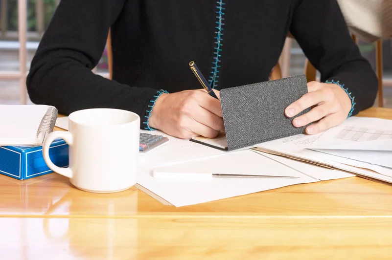 Gentlemen writing checks at his desk.