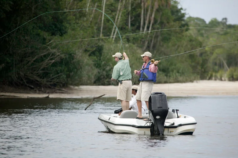 Two men fishing on a small speed boat.