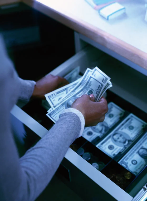 Closeup of a woman handling cash in a register.