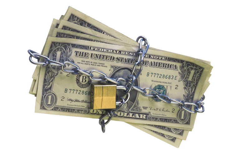 A stack a cash, with a chain and lock wrapped around it.