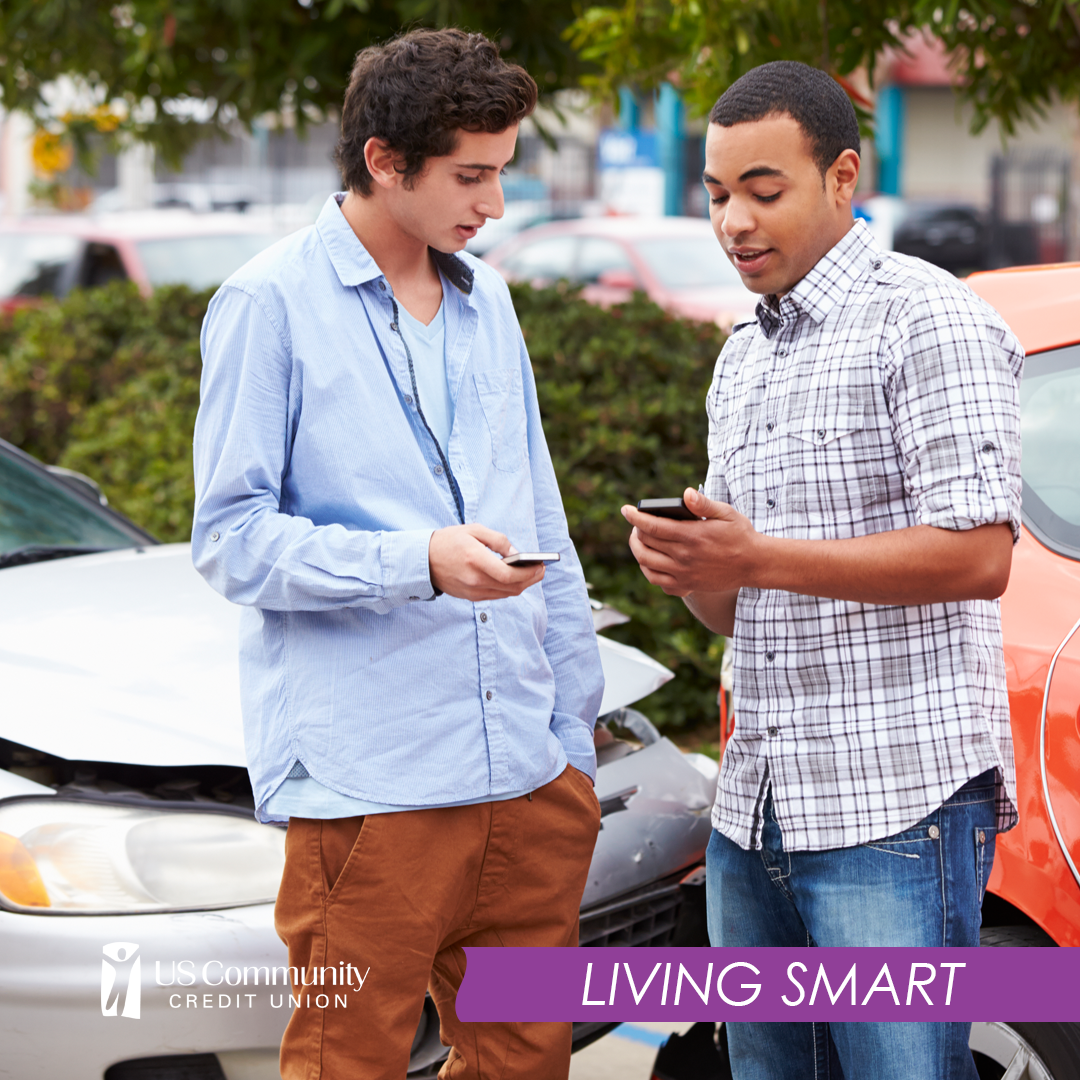 Two young men exchanging contact information after a fender bender, with the dented cars in the background.